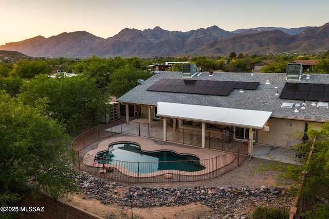 pool at dusk featuring a patio and a mountain view