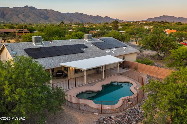 pool at dusk with a patio, central AC, and a mountain view