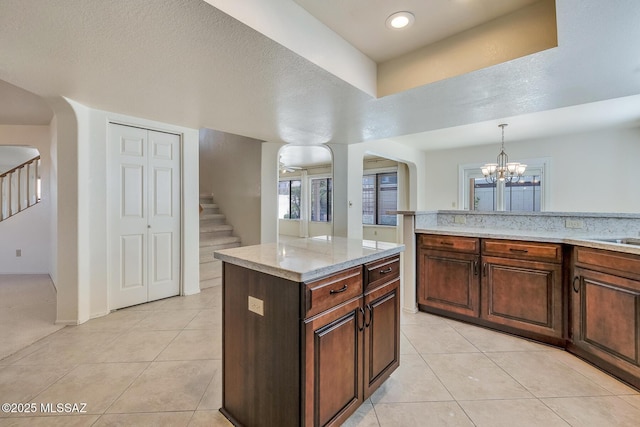 kitchen featuring an inviting chandelier, light stone counters, light tile patterned floors, and arched walkways