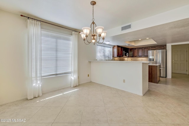 kitchen with visible vents, light tile patterned flooring, stainless steel appliances, light countertops, and a notable chandelier