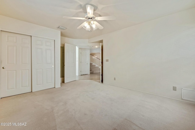 unfurnished bedroom with a closet, carpet floors, visible vents, and a ceiling fan