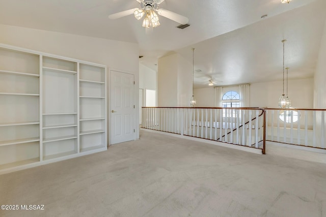 carpeted empty room with visible vents, ceiling fan with notable chandelier, and lofted ceiling