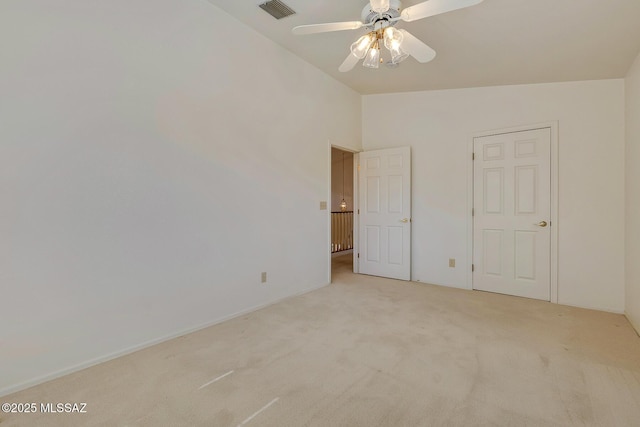 unfurnished bedroom featuring visible vents, lofted ceiling, light colored carpet, and ceiling fan