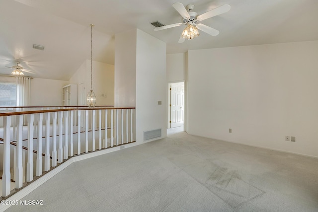 carpeted empty room featuring visible vents, ceiling fan with notable chandelier, and vaulted ceiling