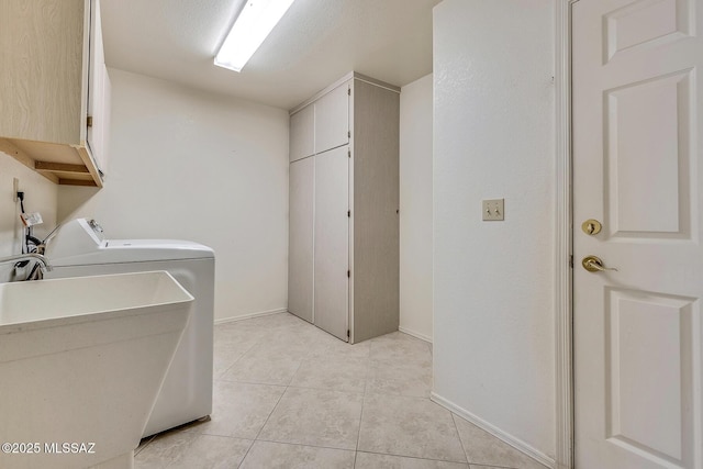 clothes washing area featuring light tile patterned floors, cabinet space, independent washer and dryer, and a sink