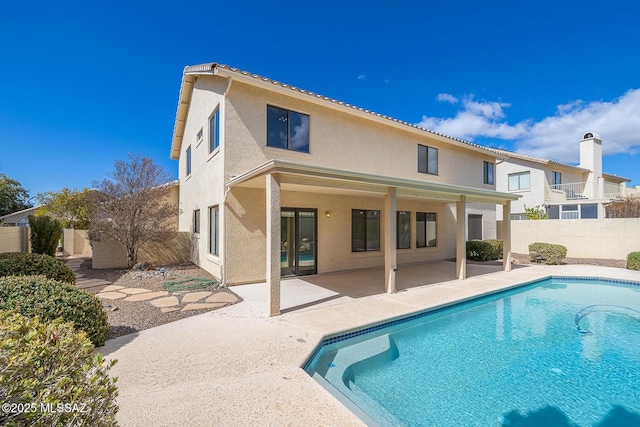 rear view of property featuring a patio area, stucco siding, fence private yard, and a fenced in pool