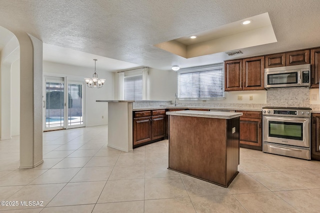 kitchen with visible vents, a sink, stainless steel appliances, light countertops, and a raised ceiling