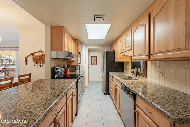 kitchen with stainless steel appliances, dark stone counters, tasteful backsplash, sink, and light tile patterned floors