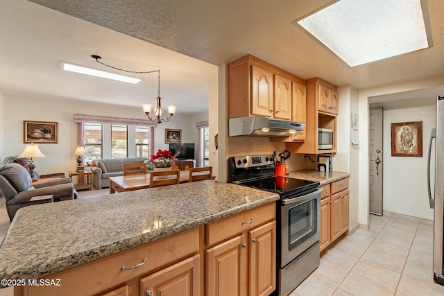 kitchen with appliances with stainless steel finishes, tasteful backsplash, a chandelier, dark stone counters, and light tile patterned flooring