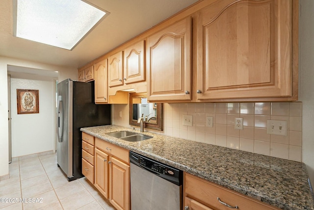 kitchen with appliances with stainless steel finishes, light tile patterned floors, sink, backsplash, and dark stone counters