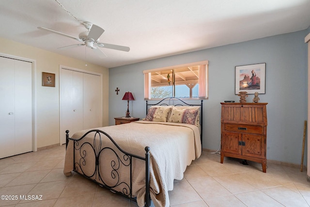 bedroom with multiple closets, light tile patterned floors, and ceiling fan