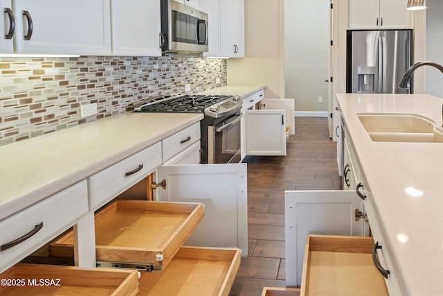 kitchen with light countertops, decorative backsplash, appliances with stainless steel finishes, white cabinetry, and a sink