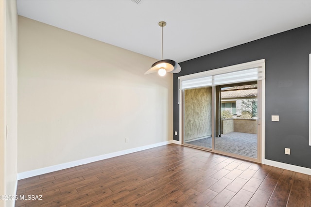 spare room with dark wood-style flooring and baseboards