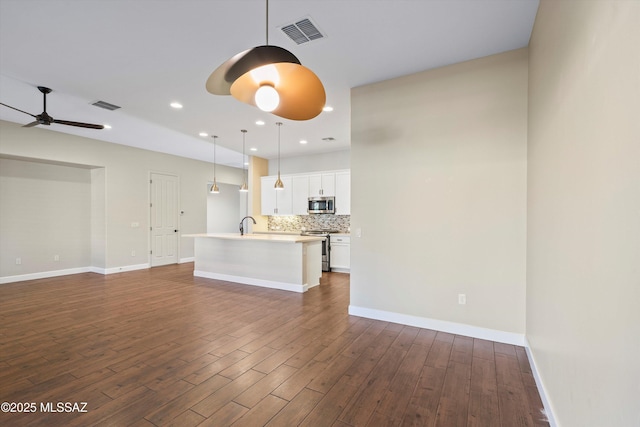 unfurnished living room featuring dark wood-style floors, baseboards, visible vents, and a ceiling fan