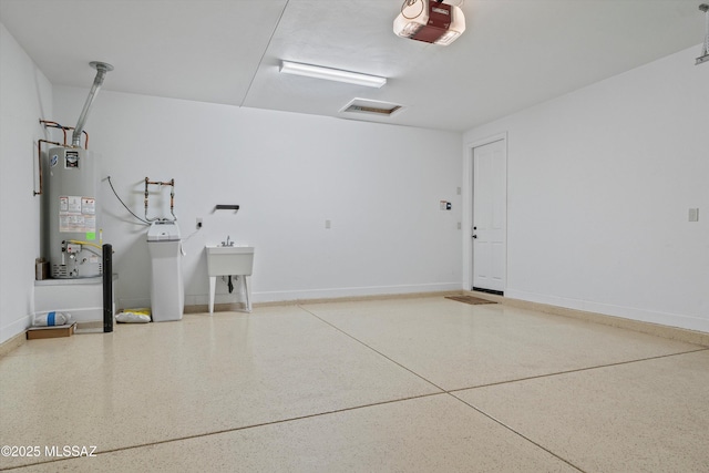 garage with a sink, baseboards, gas water heater, and a garage door opener