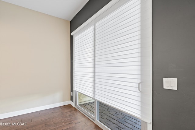 spare room featuring baseboards and dark wood finished floors