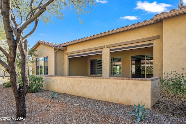 view of property exterior featuring a tiled roof and stucco siding