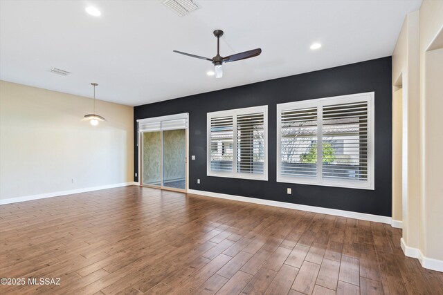 empty room featuring baseboards, visible vents, ceiling fan, and wood finished floors