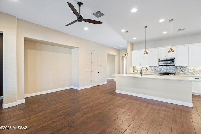 kitchen with visible vents, stainless steel microwave, and backsplash