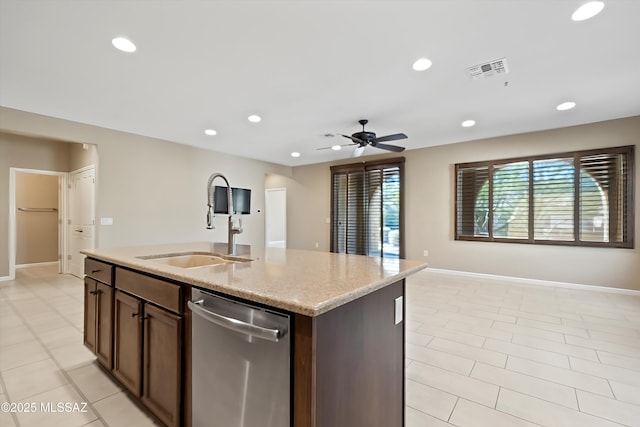 kitchen featuring an island with sink, sink, stainless steel dishwasher, ceiling fan, and light stone countertops