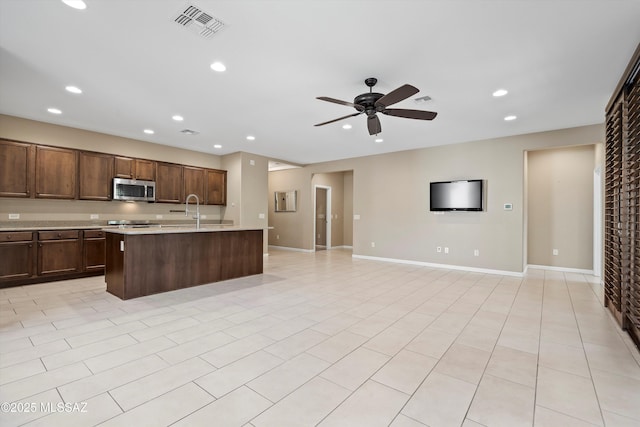 kitchen with ceiling fan, sink, a kitchen island with sink, and light tile patterned floors