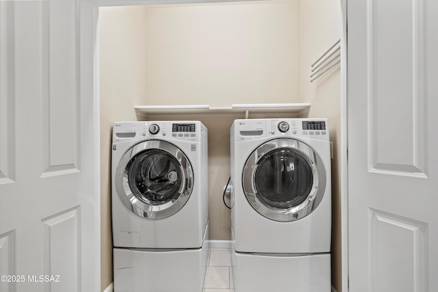 laundry room with washer and dryer and light tile patterned flooring