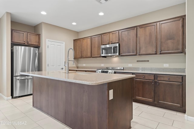 kitchen with a kitchen island with sink, dark brown cabinetry, and appliances with stainless steel finishes