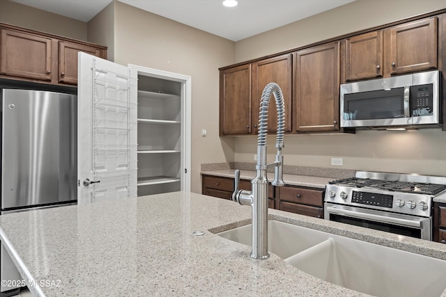 kitchen featuring light stone counters, sink, and appliances with stainless steel finishes