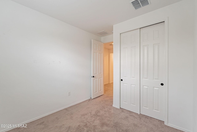 unfurnished bedroom featuring a closet and light colored carpet