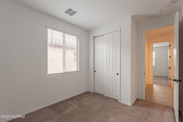 unfurnished bedroom with light carpet and a closet