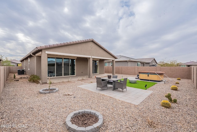 back of house with central air condition unit, a hot tub, a patio, and a fire pit