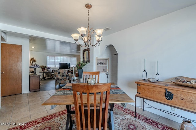 tiled dining room with an inviting chandelier