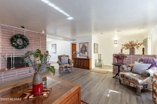 living room featuring wood-type flooring and a brick fireplace