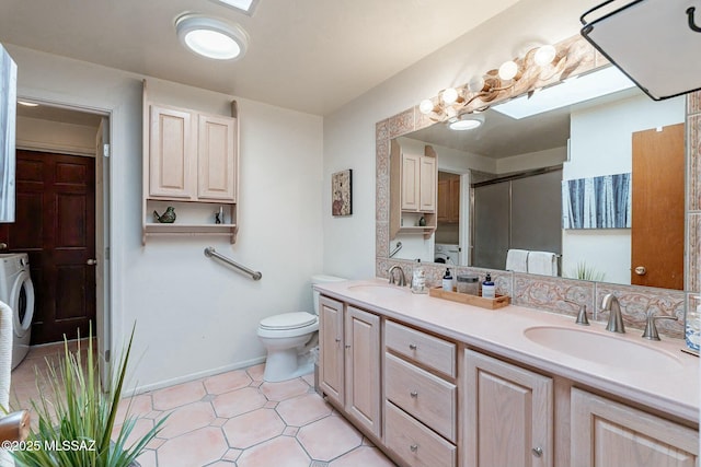 bathroom featuring washer / clothes dryer, a shower with door, vanity, and toilet