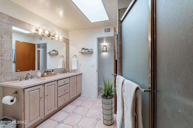 bathroom with vanity, a skylight, and a shower with door