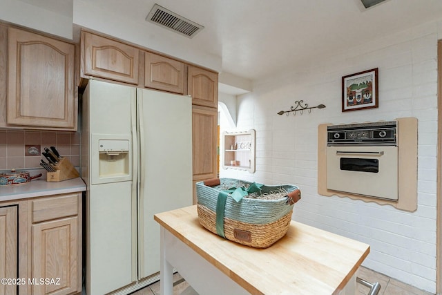 kitchen featuring light brown cabinetry, tasteful backsplash, white appliances, butcher block countertops, and light tile patterned flooring