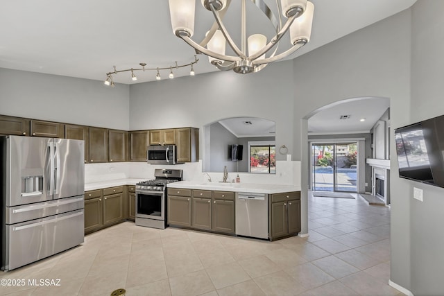 kitchen with sink, hanging light fixtures, a chandelier, light tile patterned flooring, and appliances with stainless steel finishes