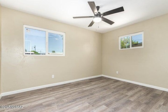 spare room with ceiling fan, plenty of natural light, and light wood-type flooring