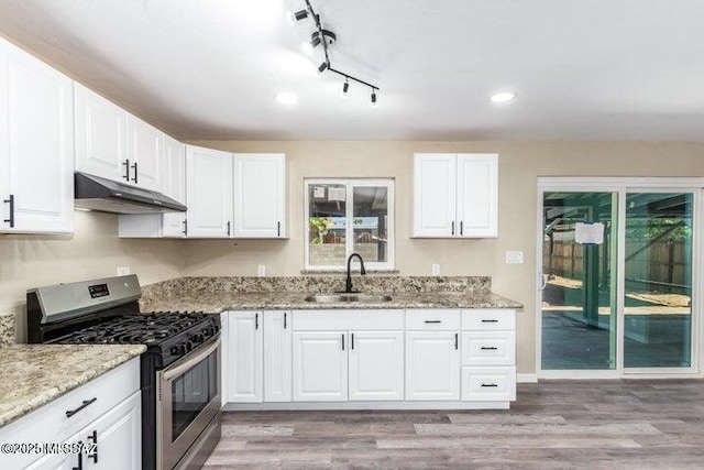 kitchen with gas stove, sink, light stone counters, light hardwood / wood-style flooring, and white cabinets