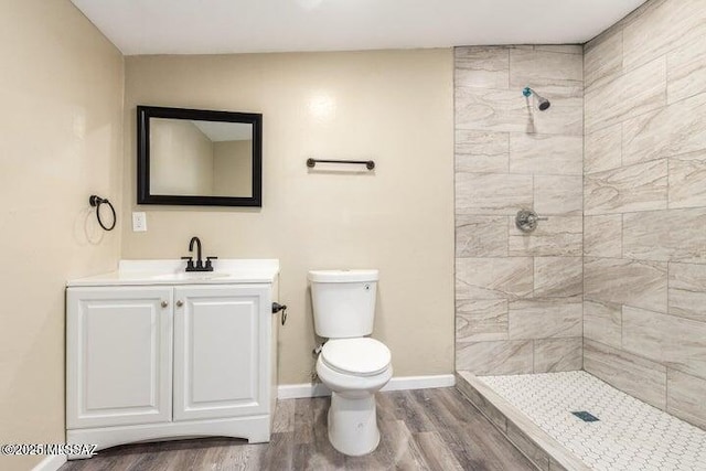 bathroom featuring tiled shower, hardwood / wood-style flooring, vanity, and toilet