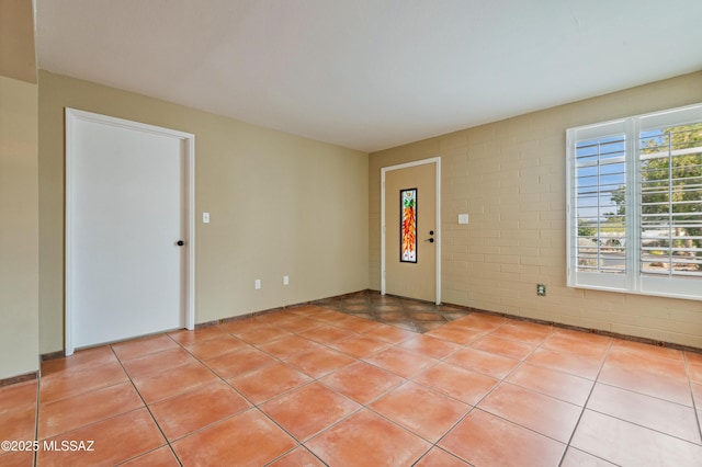 tiled spare room with brick wall