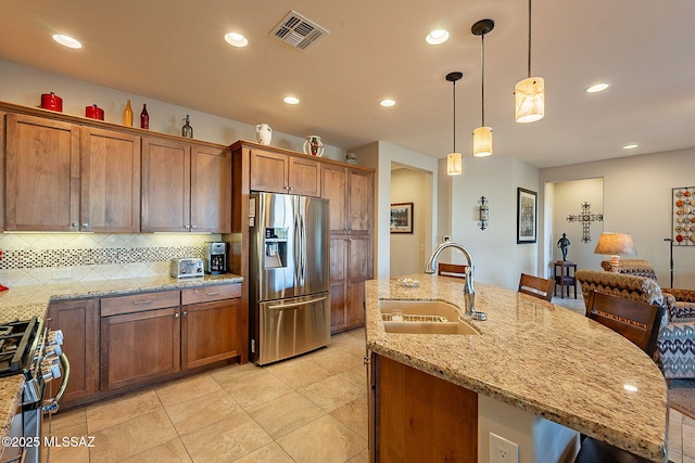 kitchen with a kitchen island with sink, sink, decorative backsplash, decorative light fixtures, and stainless steel appliances