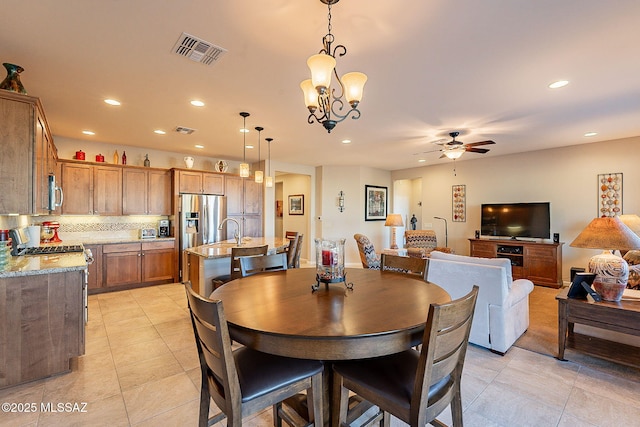 tiled dining space with ceiling fan with notable chandelier and sink