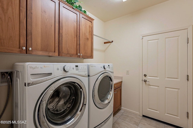 laundry room with washer and clothes dryer, cabinets, and light tile patterned floors