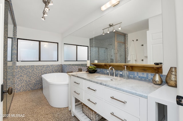 bathroom featuring vanity, tile patterned flooring, decorative backsplash, a tub to relax in, and tile walls