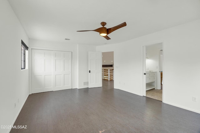 unfurnished bedroom with ensuite bathroom, ceiling fan, dark hardwood / wood-style floors, and a closet