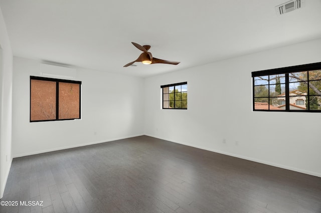 spare room with ceiling fan, dark hardwood / wood-style flooring, and a wall mounted air conditioner