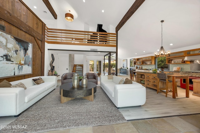 living room featuring wood-type flooring, an inviting chandelier, high vaulted ceiling, and beam ceiling