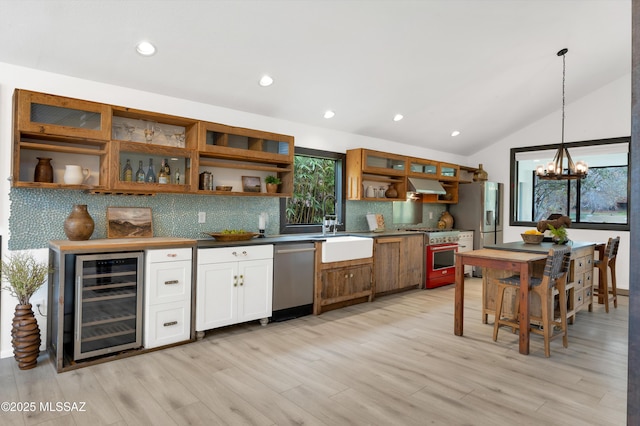 kitchen featuring stainless steel appliances, extractor fan, vaulted ceiling, decorative light fixtures, and wine cooler