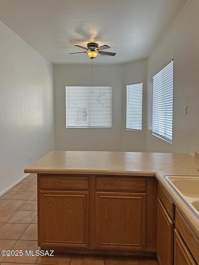 kitchen with sink, kitchen peninsula, ceiling fan, and light tile patterned flooring